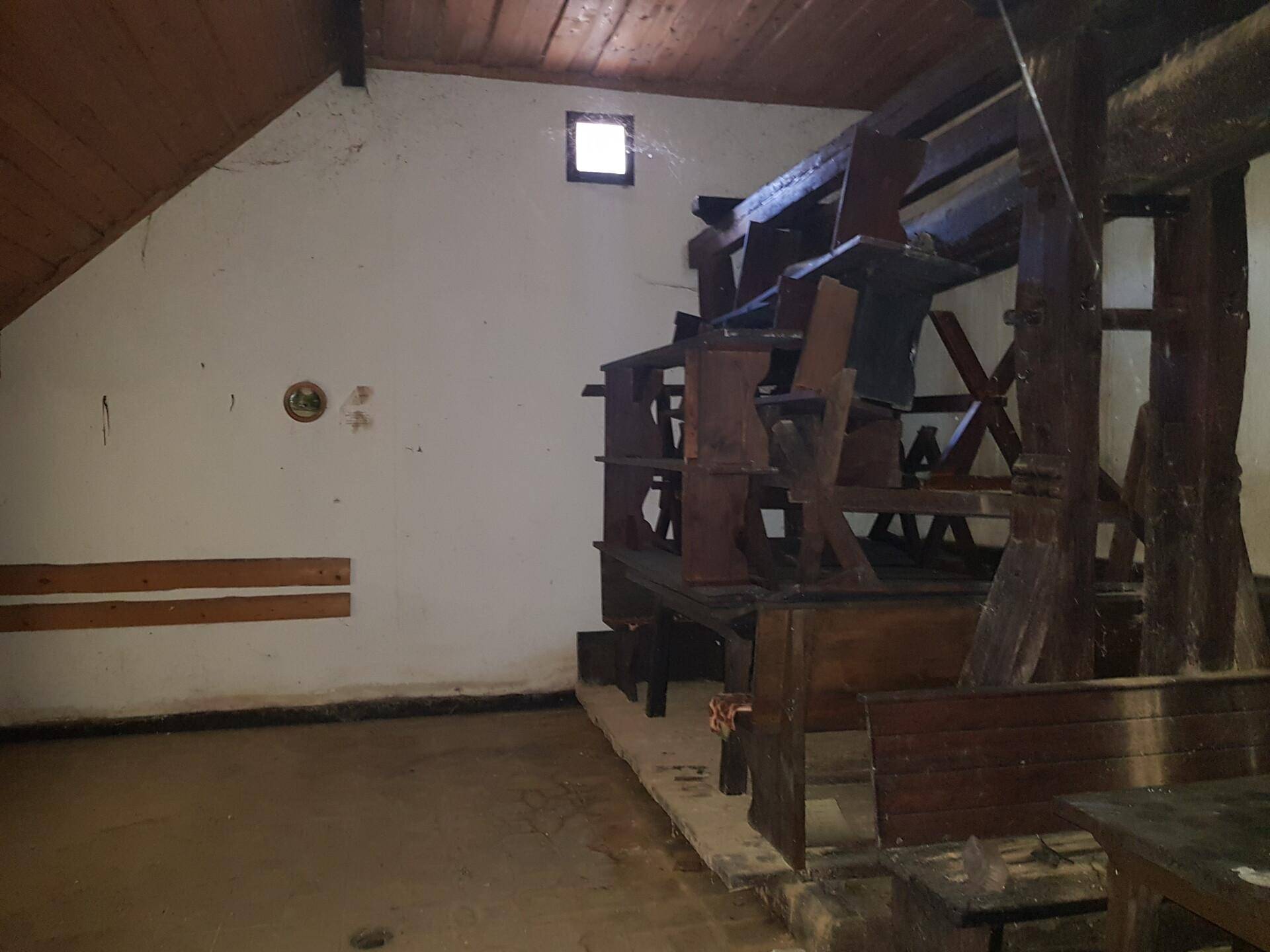 Rustikaler Innenraum mit Holzbalken und einer großen Holzkonstruktion, möglicherweise einer alten Mühle.
