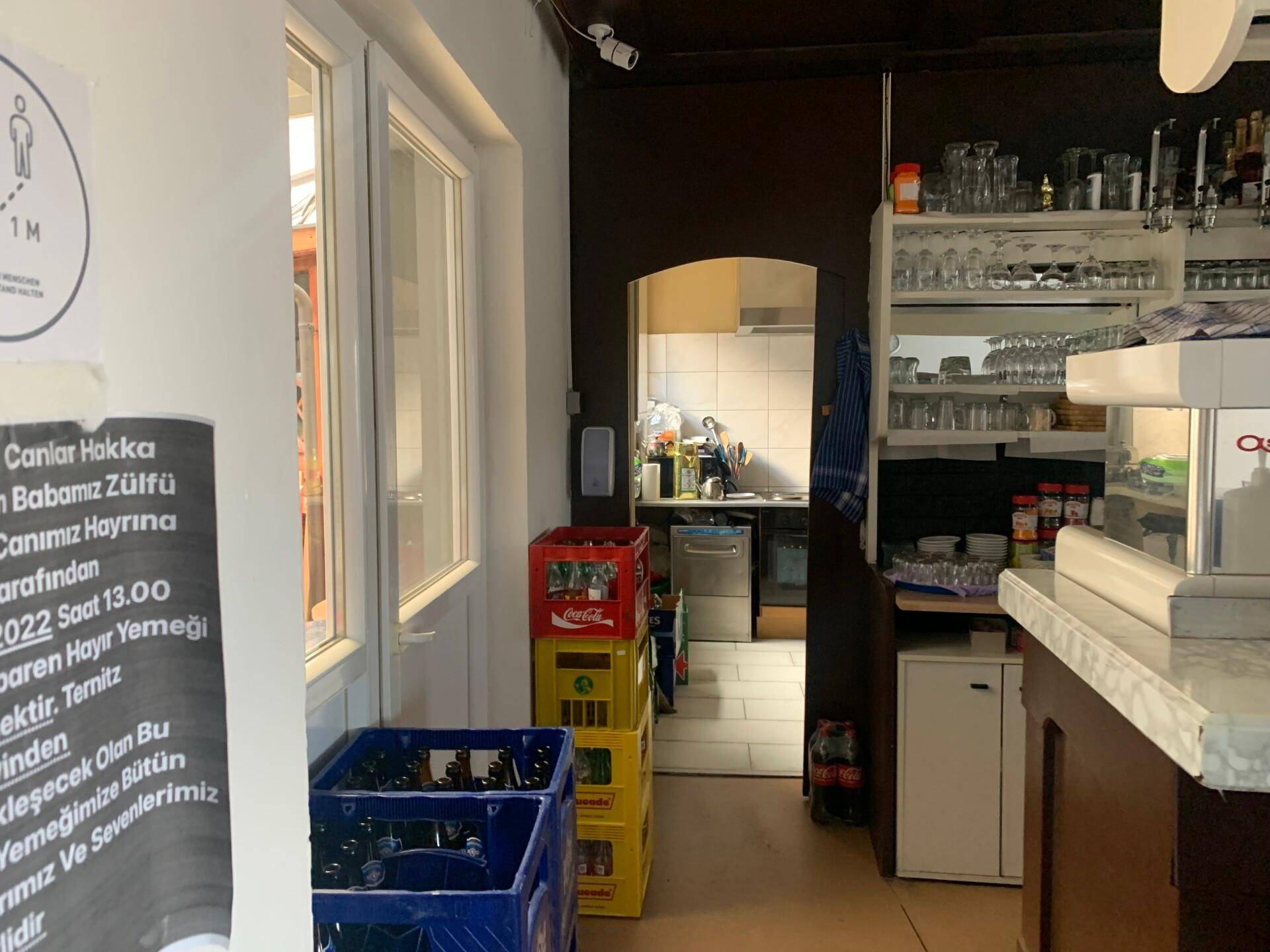 Barbereich mit Gläsern und Kaffeemaschine, der einen Durchgang zur dahinterliegenden Küche bietet.