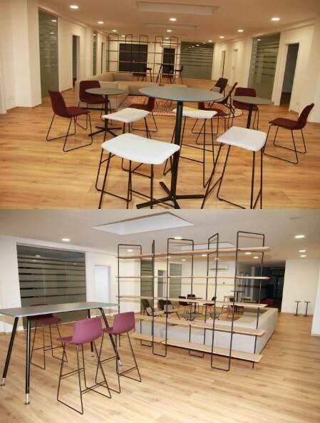 Moderner Lounge-Bereich mit bequemen Sofas, Tischen und einem großen Regal als Raumteiler, schafft eine einladende Atmosphäre.