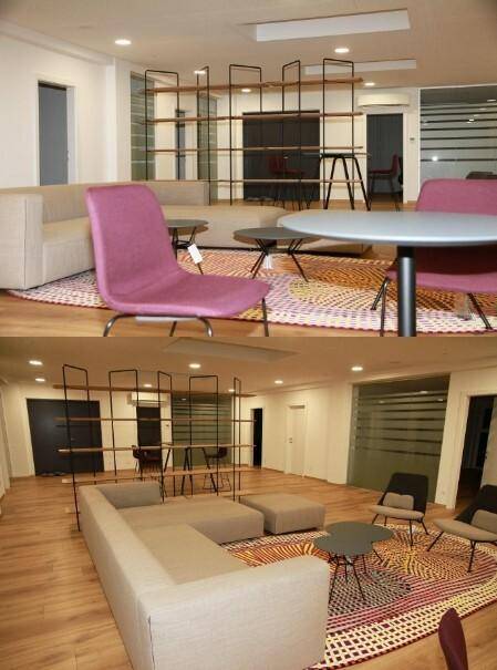 Moderner Lounge-Bereich mit bequemen Sofas, Tischen und einem großen Regal als Raumteiler, schafft eine einladende Atmosphäre.