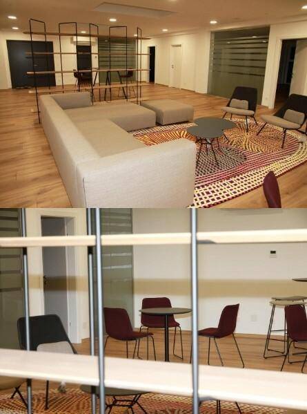 Geräumiger Lounge-Bereich mit bequemen Sofas, Tischen und einem großen Regal als Raumteiler, perfekt für informelle Treffen.