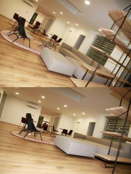 Geräumiger Lounge-Bereich mit bequemen Sofas, Tischen und einem großen Regal als Raumteiler, ideal für Entspannung.