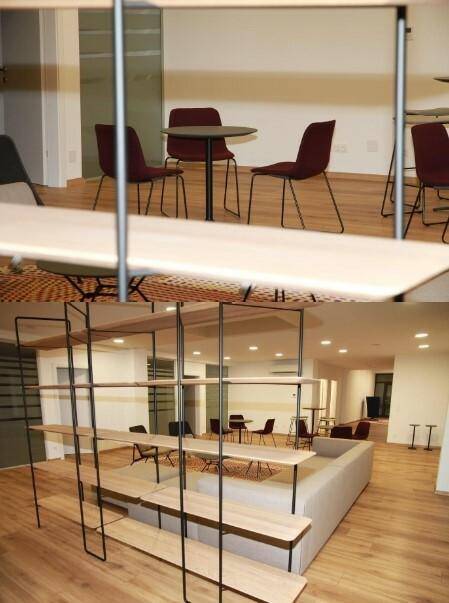 Moderner Lounge-Bereich mit bequemen Sofas, Tischen und einem großen Regal als Raumteiler, schafft eine einladende Atmosphäre.
