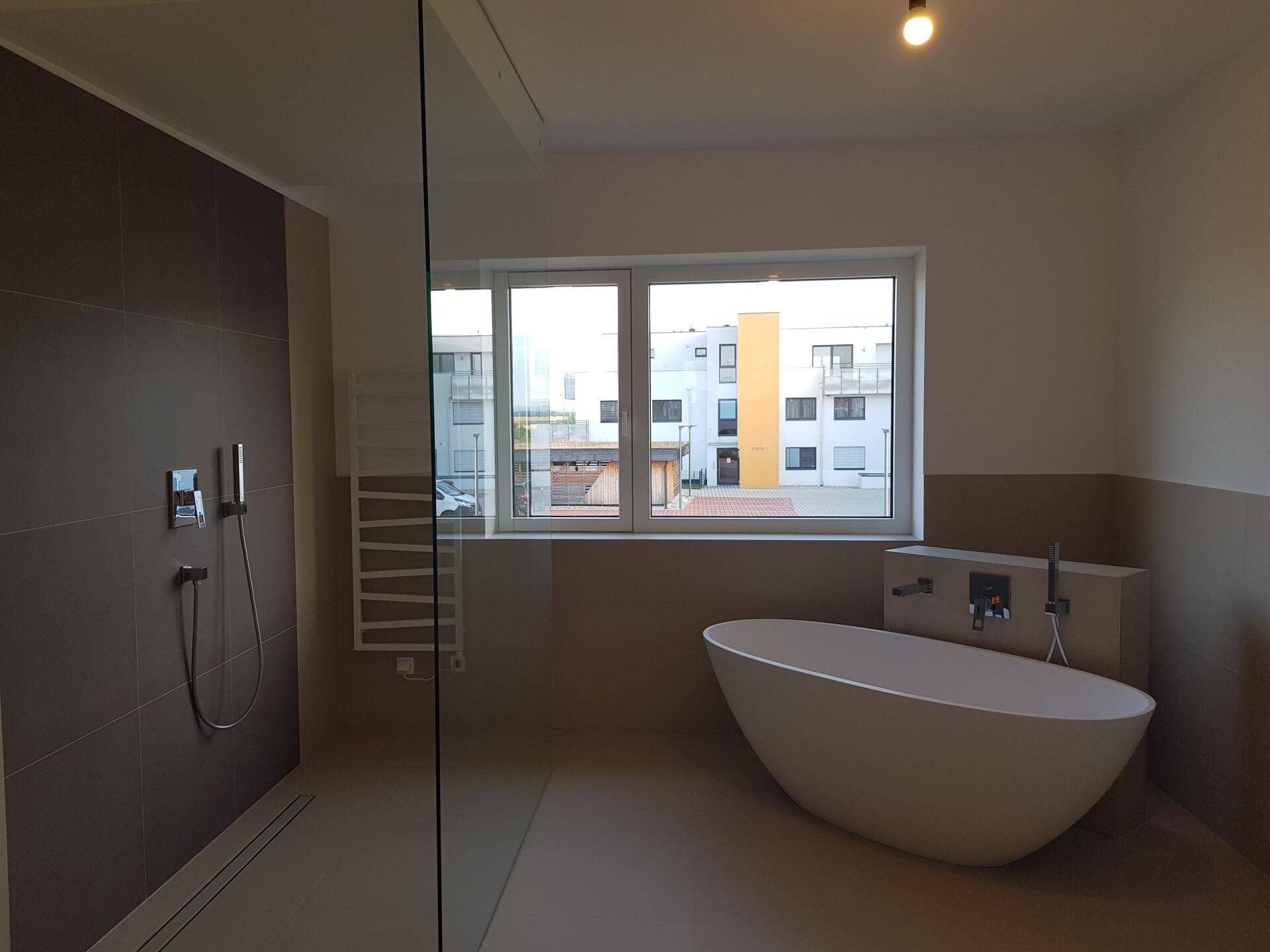 Modernes Badezimmer mit freistehender Badewanne, ebenerdiger Dusche und Fenster.
