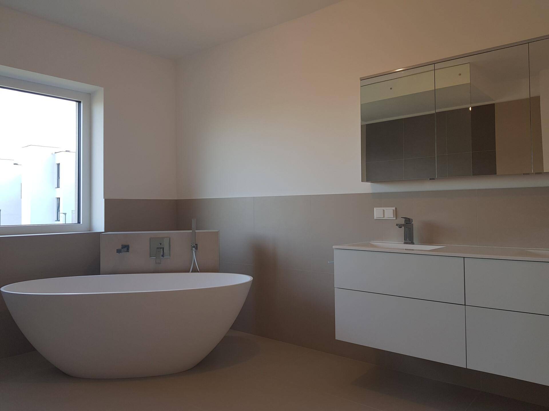 Elegantes Badezimmer mit Doppelwaschbecken, Spiegelschrank und freistehender Badewanne.