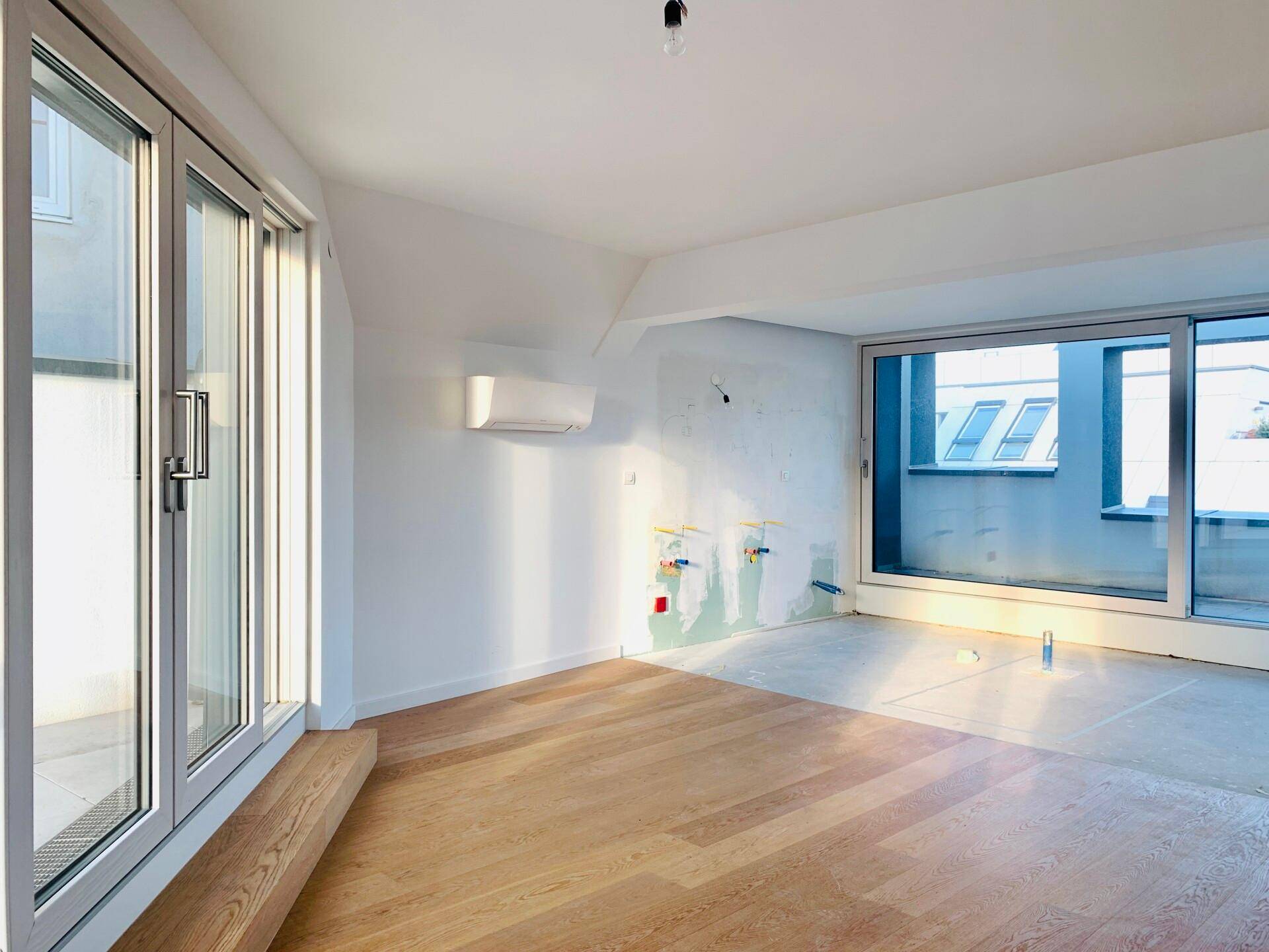 Heller Raum mit Holzboden und großen Schiebetüren, vorbereitet für Installationen, mit Klimaanlage.