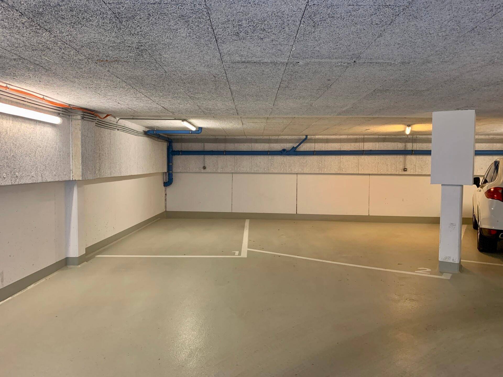 Tiefgarage mit markierten Parkplätzen und Beleuchtung, sauber und funktional.