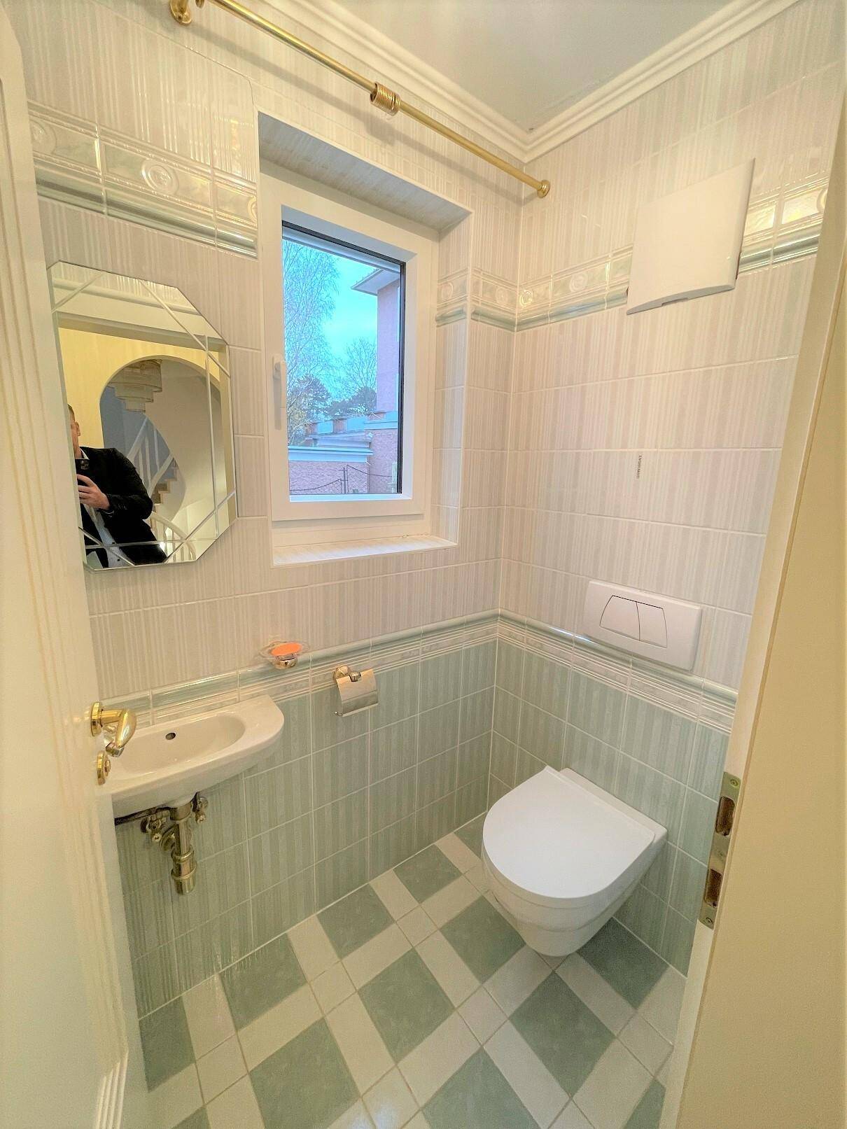 Kleines Gäste-WC mit Fenster, Wand-WC und kompaktem Waschbecken.