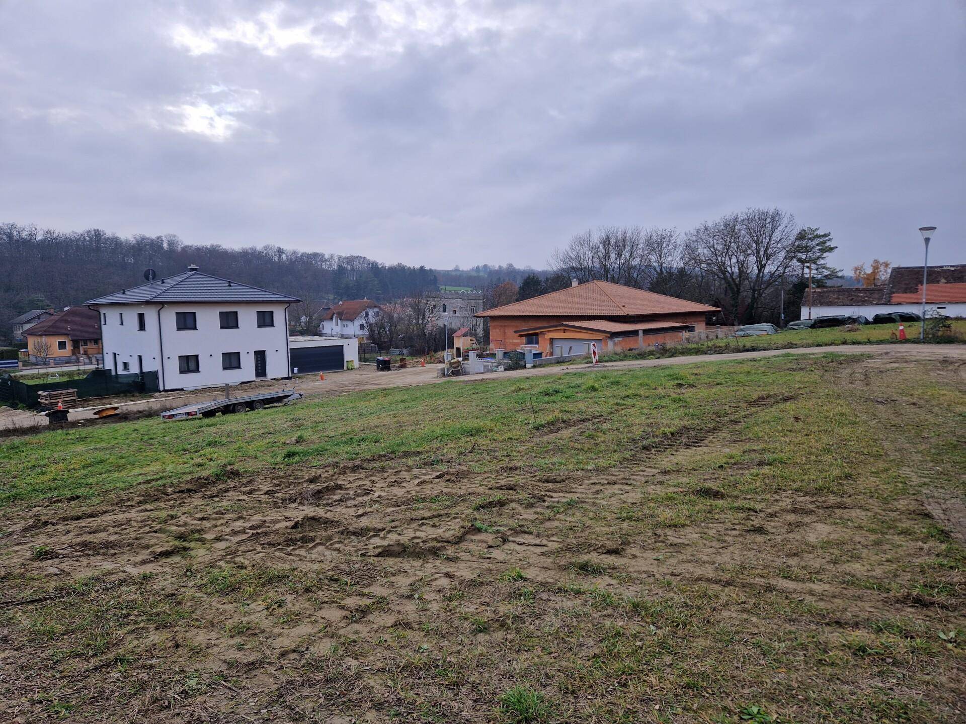 Blick auf ein neues Haus und ein im Bau befindliches Gebäude in einer ländlichen Umgebung.