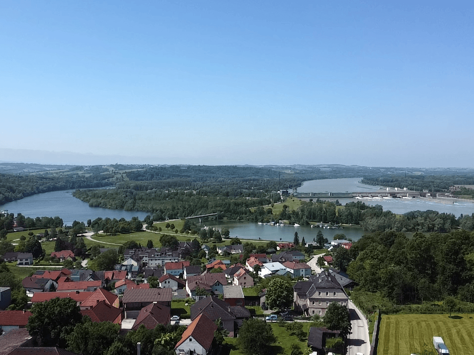 Panoramablick über eine Kleinstadt am Fluss mit weiten Landschaften und blauem Himmel.