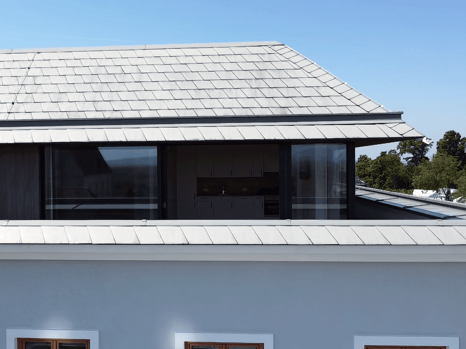 Nahaufnahme des Dachgeschosses mit großen Panoramafenstern und moderner Dachkonstruktion.