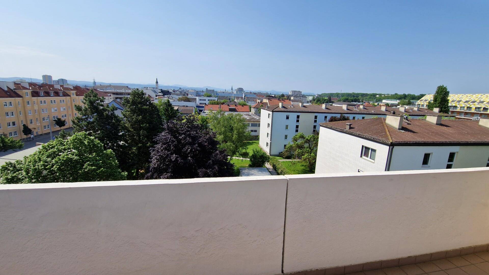 Balkon mit weitem Blick über die Stadt und umliegende Wohngebäude.
