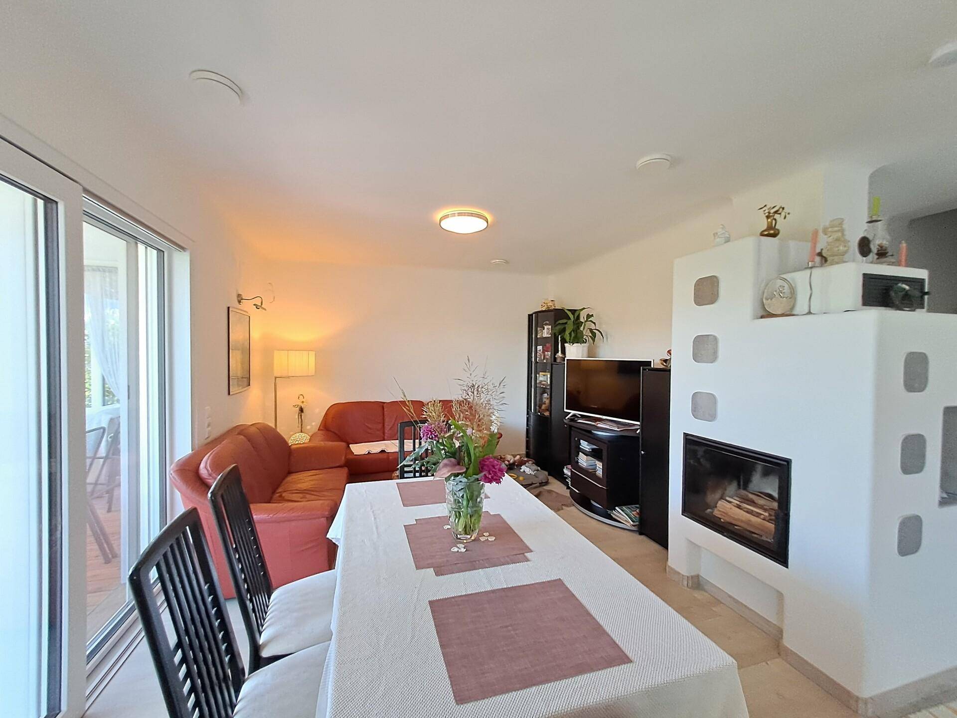 Heller Wohn-Essbereich mit modernem Kaminofen, Ledersofa und direktem Zugang zur Terrasse.