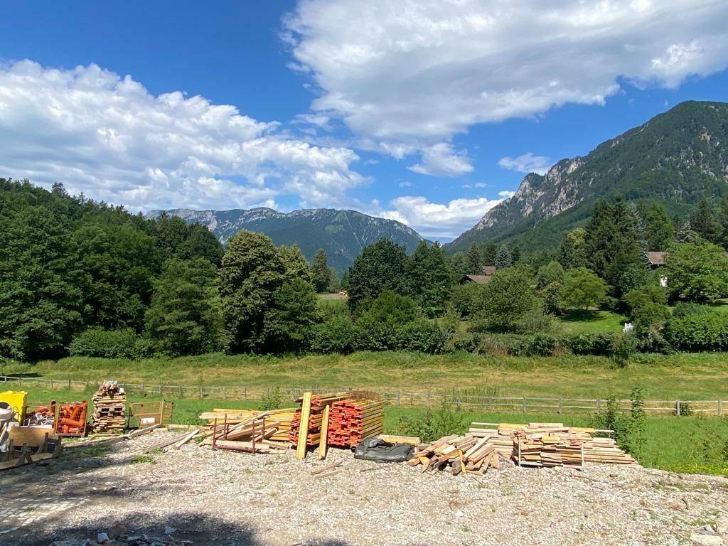 Baustelle mit Baumaterialien und weitem Blick auf die umliegende Berglandschaft und Wälder.
