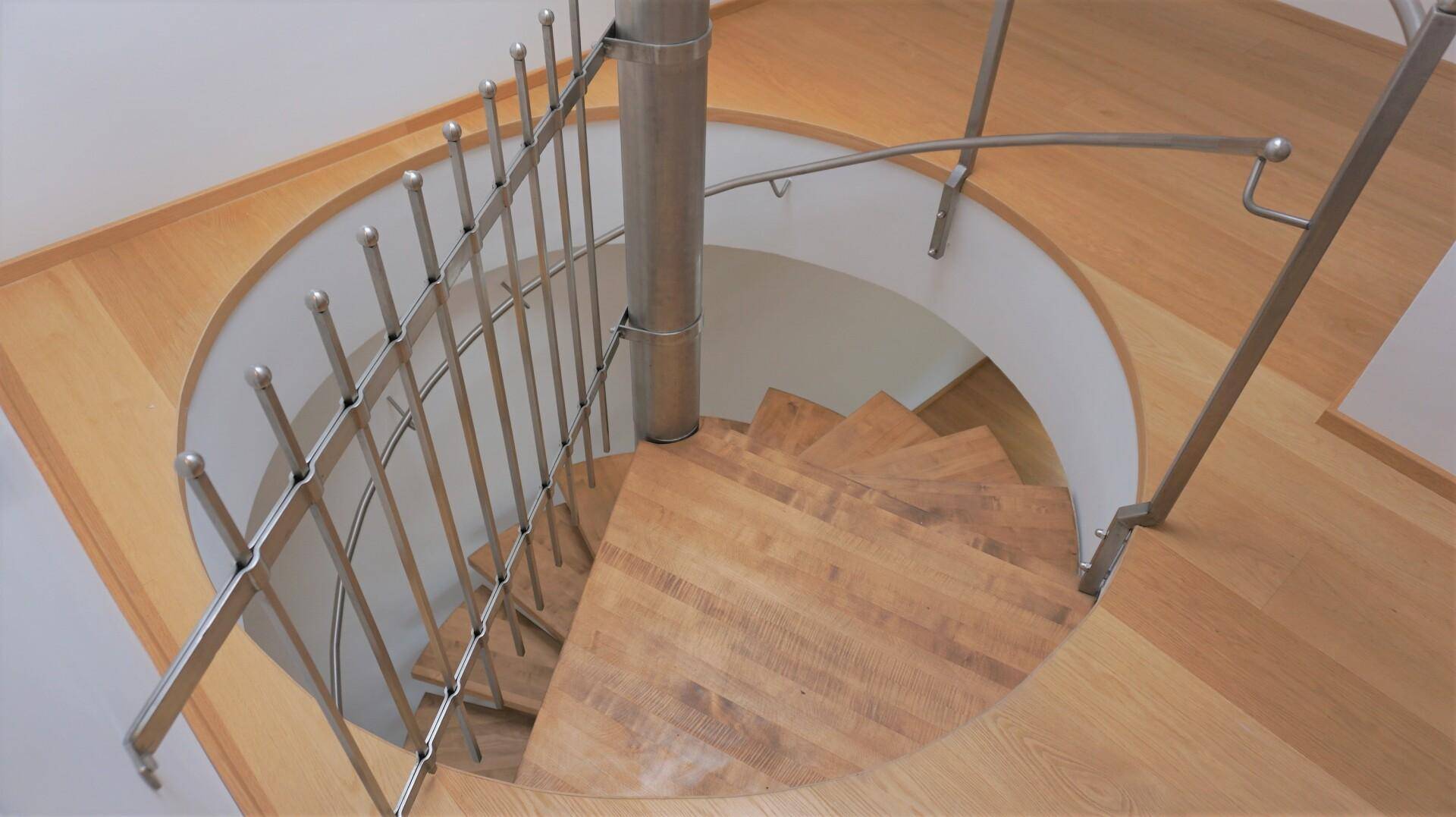 Elegante Wendeltreppe aus Holz mit Metallgeländer, die verschiedene Ebenen verbindet.