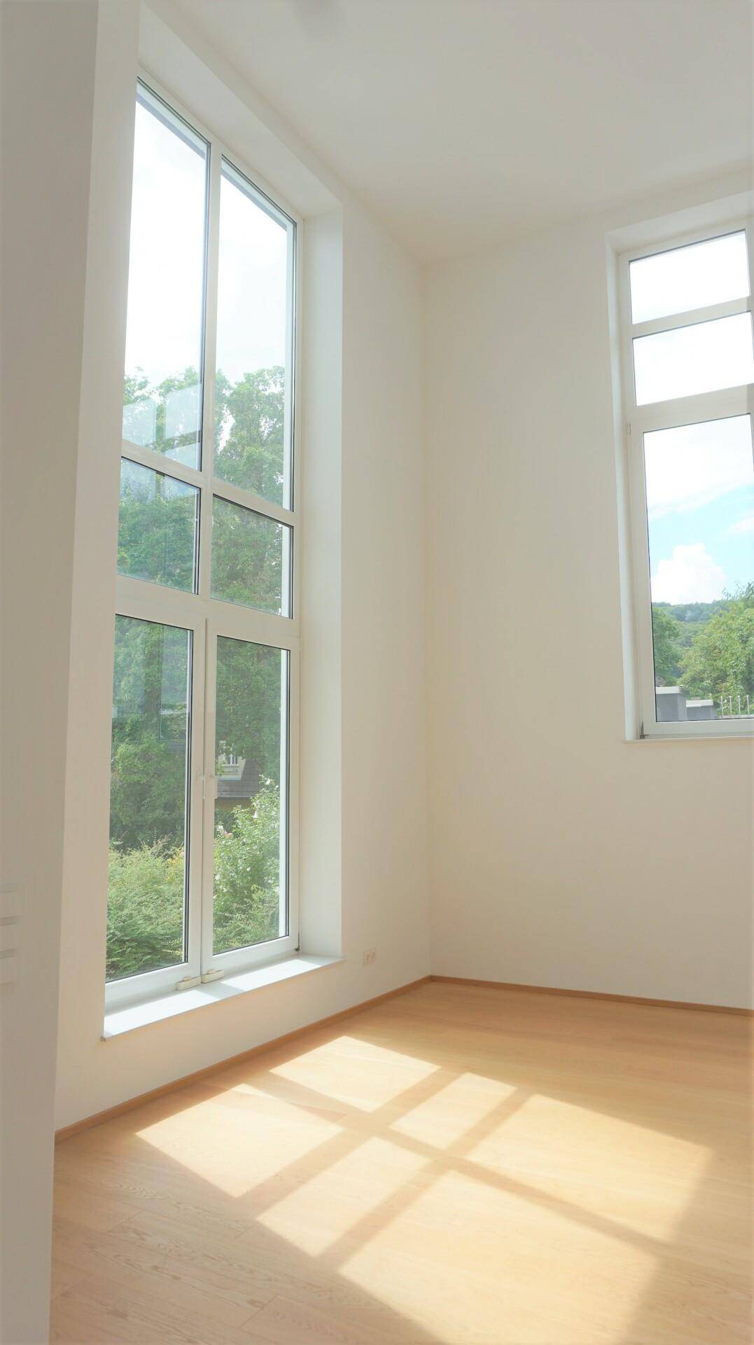 Lichtdurchfluteter Raum mit hohen Decken und großen Fenstern, die viel Tageslicht hereinlassen.