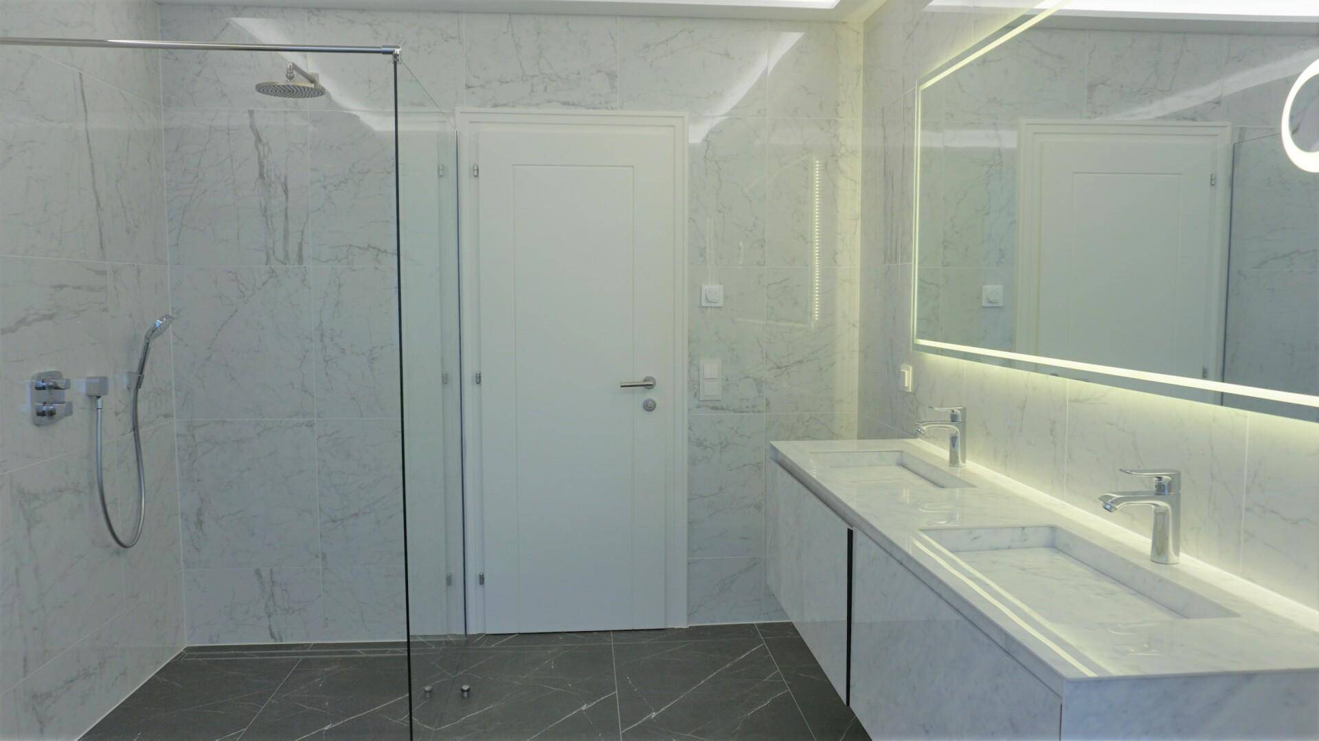 Modernes Badezimmer mit Marmorfliesen, Doppelwaschbecken und großer begehbarer Dusche.
