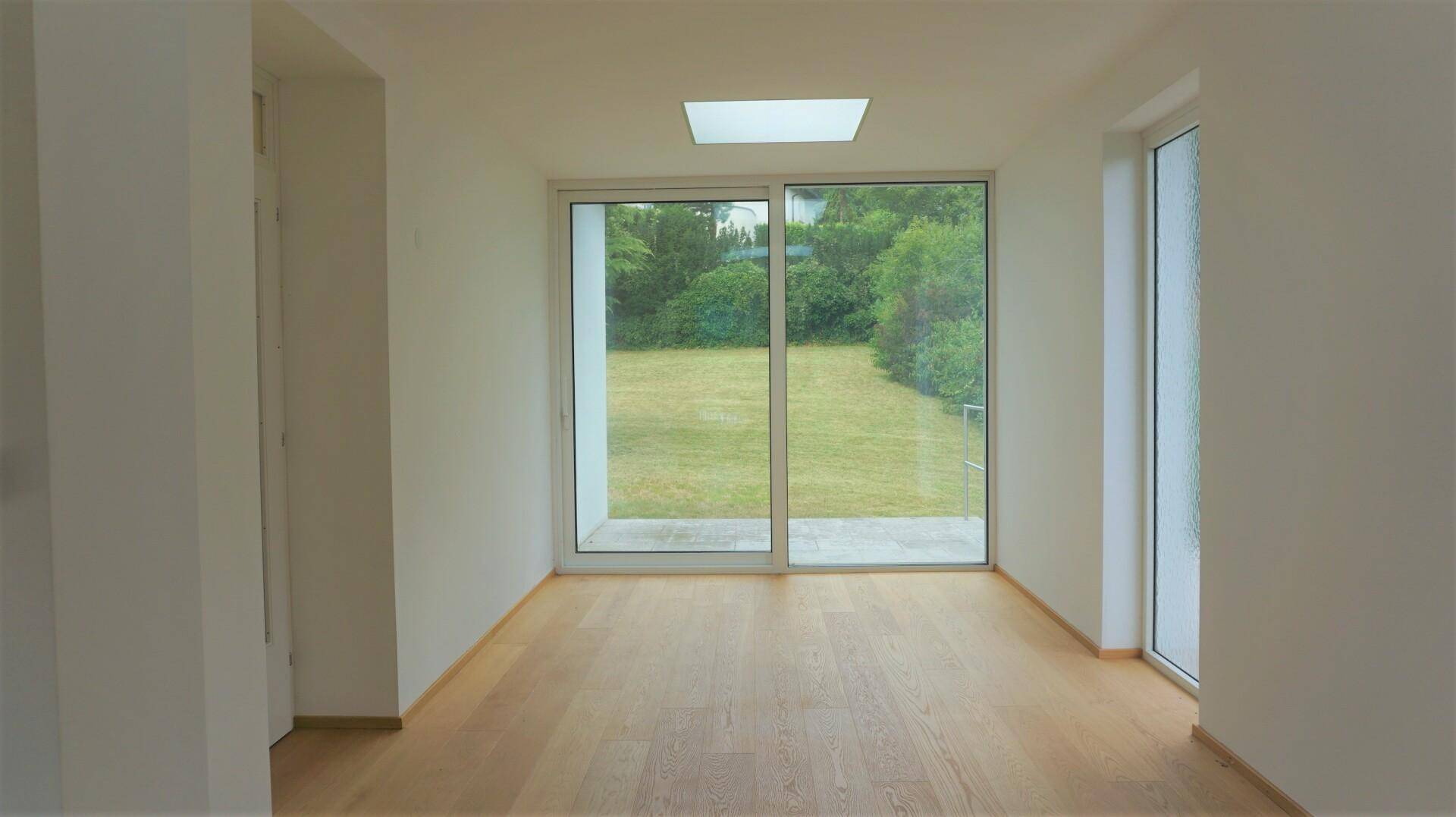 Heller Raum mit großen Schiebetüren zum Garten und Blick ins Grüne.