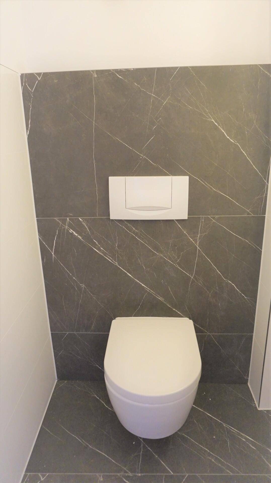 Modernes Wand-WC mit dunklen Marmorfliesen und minimalistischem Design.