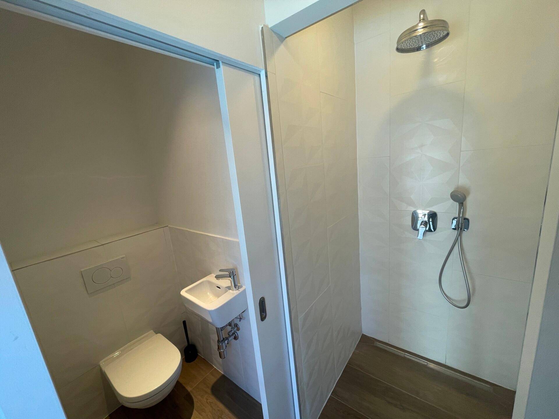 Modernes Badezimmer mit begehbarer Dusche, Wand-WC und hellen Fliesen.