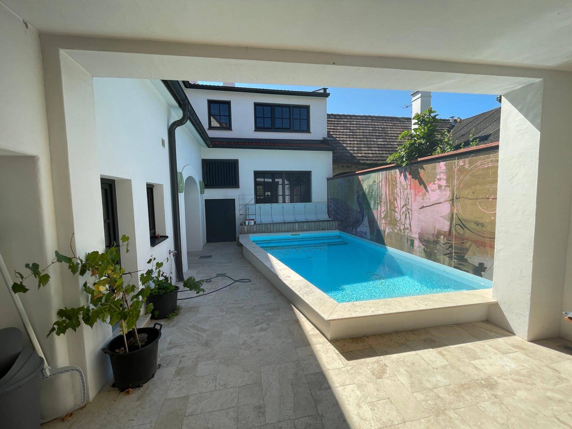 Kleiner, moderner Pool im Innenhof mit gefliestem Bereich und Blick auf das Gebäude.