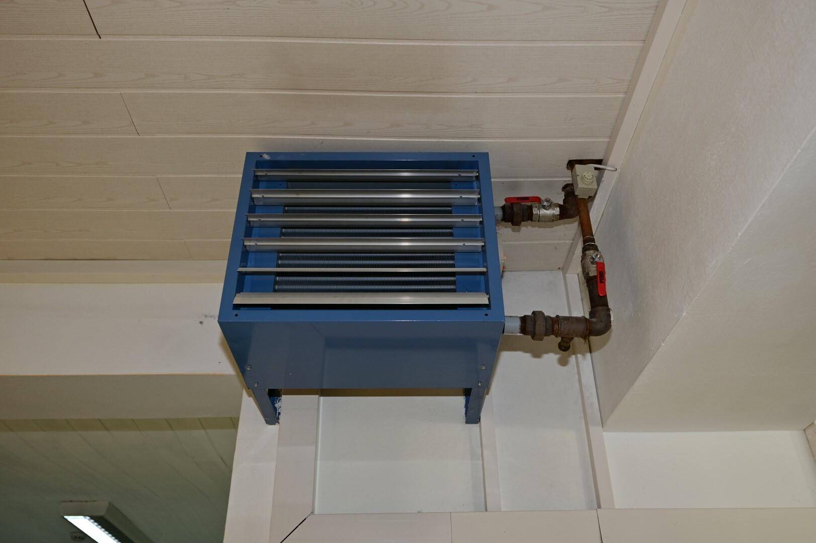 Deckenmontierte Heizungsanlage mit sichtbaren Rohren in einem Innenraum, die für angenehme Temperaturen sorgt.