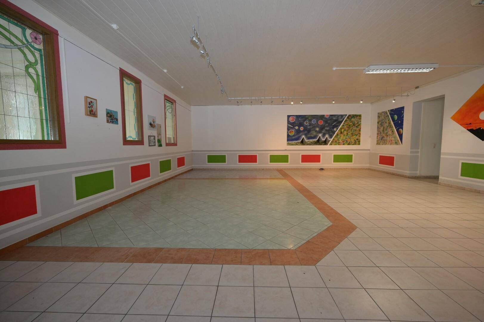 Bereich des Saals mit farbigen Wandpaneelen und Kunstwerken, der eine lebendige und inspirierende Atmosphäre schafft.