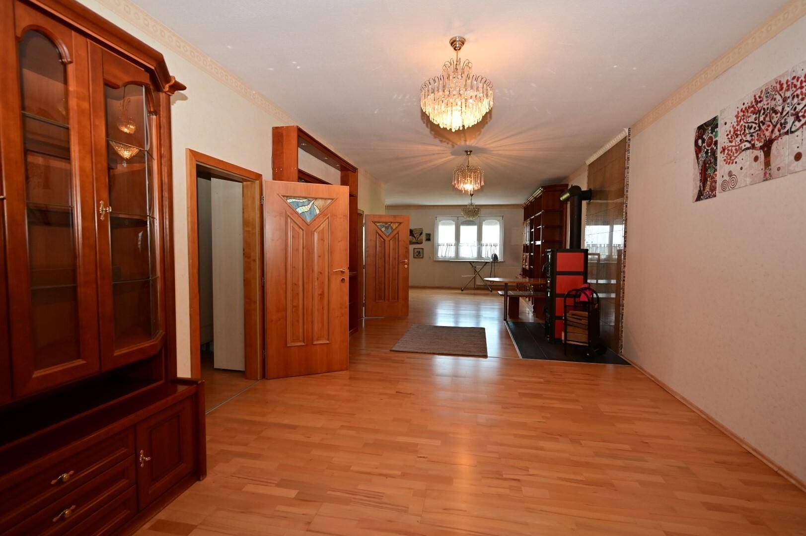 Heller Wohnbereich mit Holzboden, Kronleuchtern und einem Holzschrank, der Gemütlichkeit und Eleganz ausstrahlt.