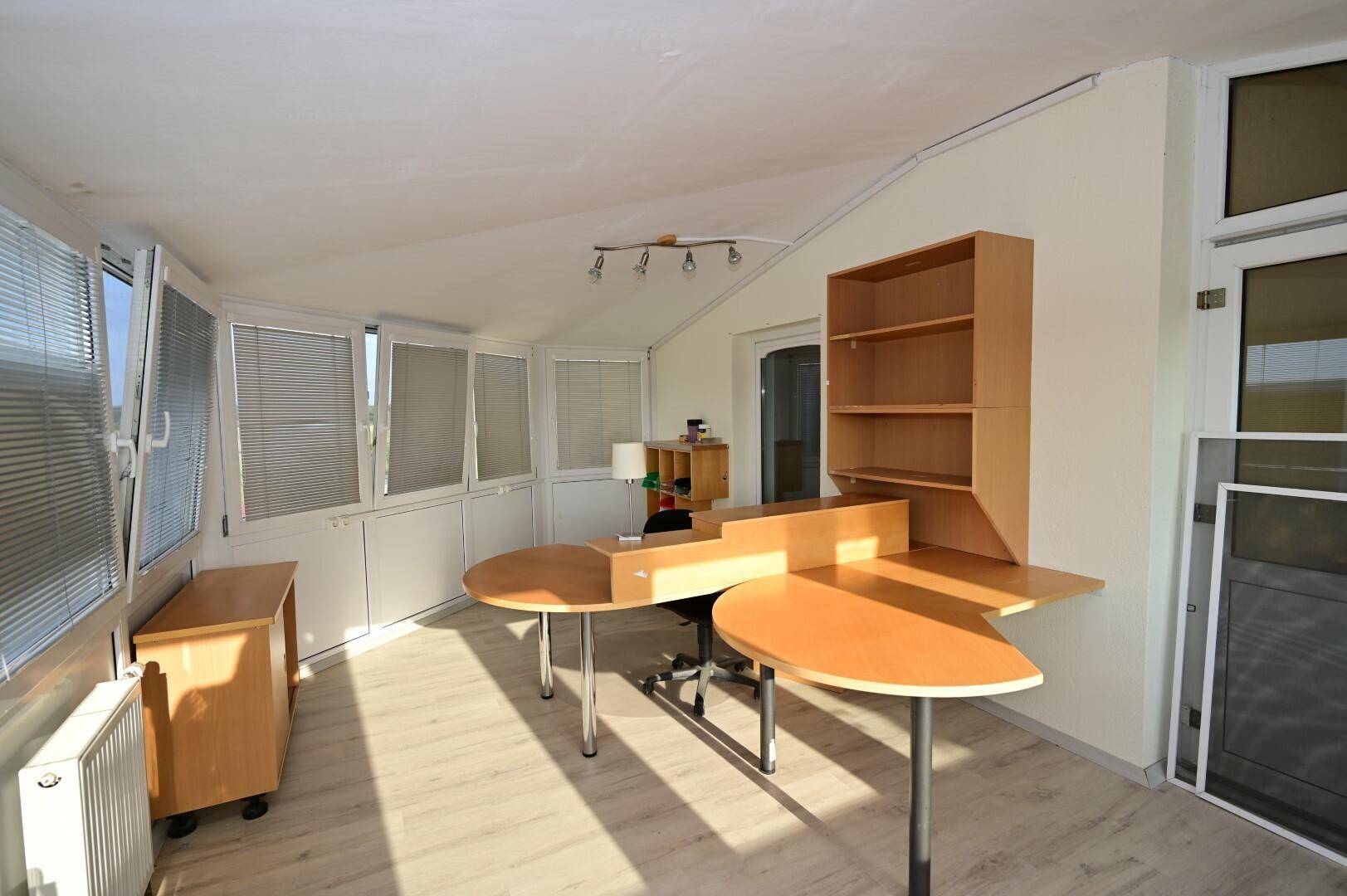Heller Wintergarten, der als Büro genutzt wird, mit großen Fenstern und viel Tageslicht, ideal für produktives Arbeiten.