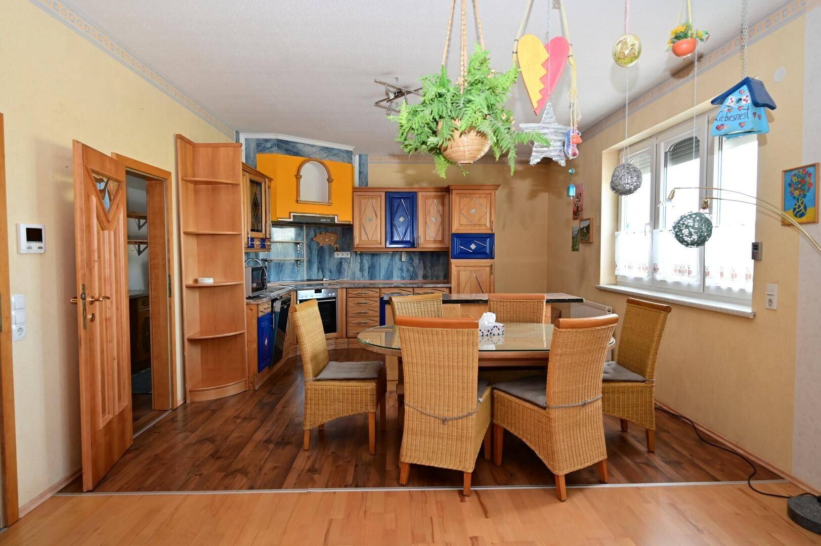 Gemütlicher Wohnküchenbereich mit Holzboden, Esstisch und traditionellen Küchenschränken, ideal für Familienessen.