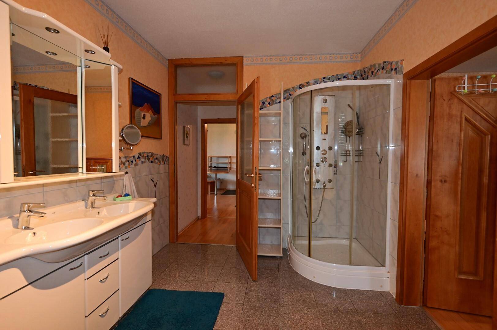 Badezimmer mit Duschkabine, Doppelwaschbecken und Fliesenboden, funktional und hell, ideal für den täglichen Gebrauch.