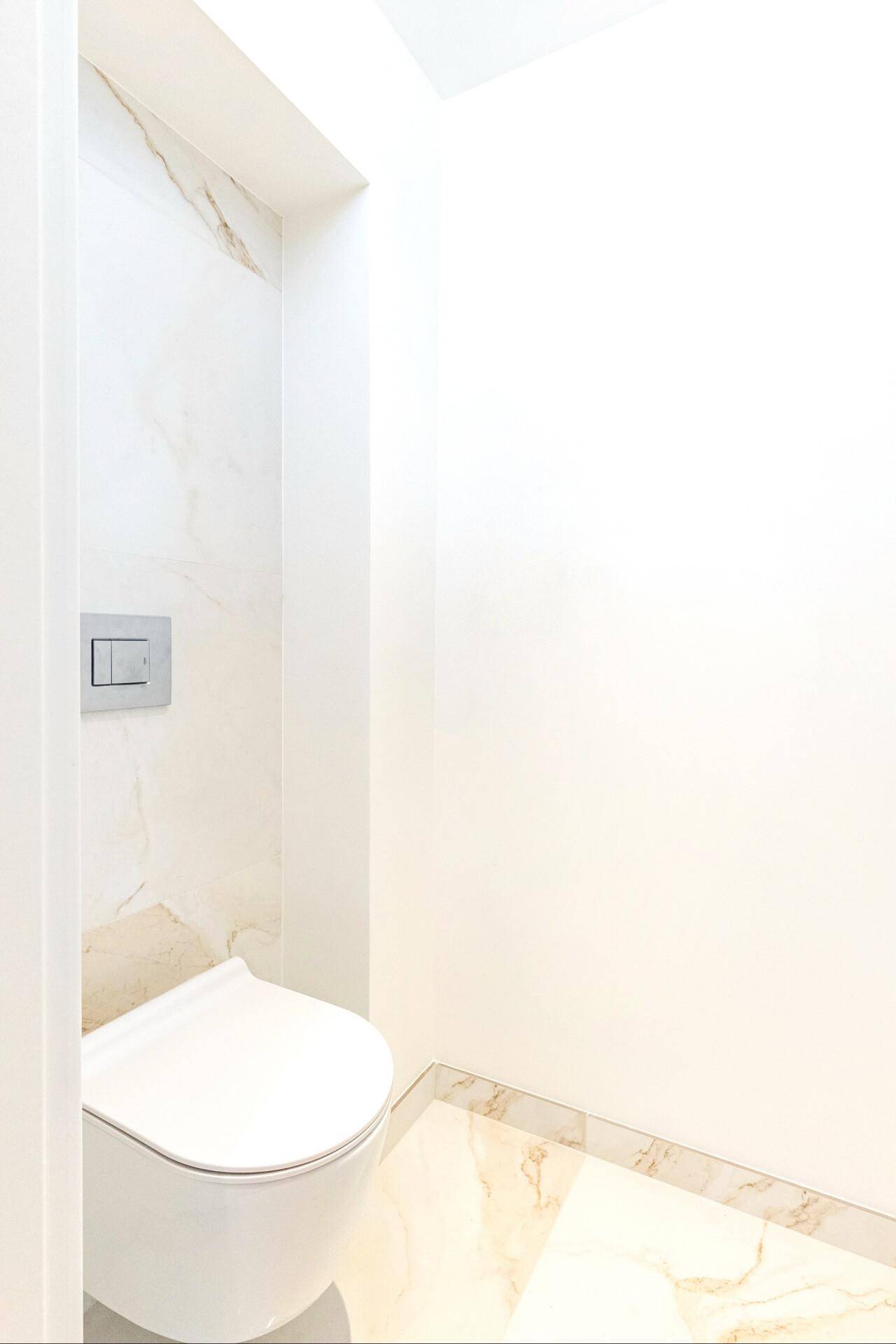 Modernes Gäste-WC mit wandhängender Toilette und eleganten Marmorfliesen, minimalistisch gestaltet.