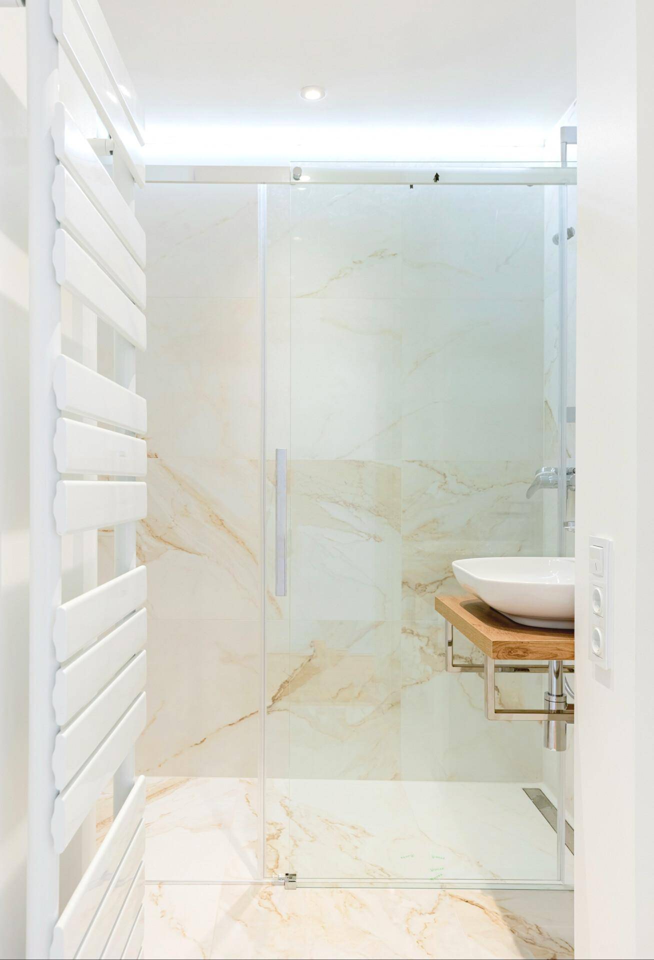 Elegantes Badezimmer mit begehbarer Dusche, modernem Waschbecken und beheiztem Handtuchhalter.