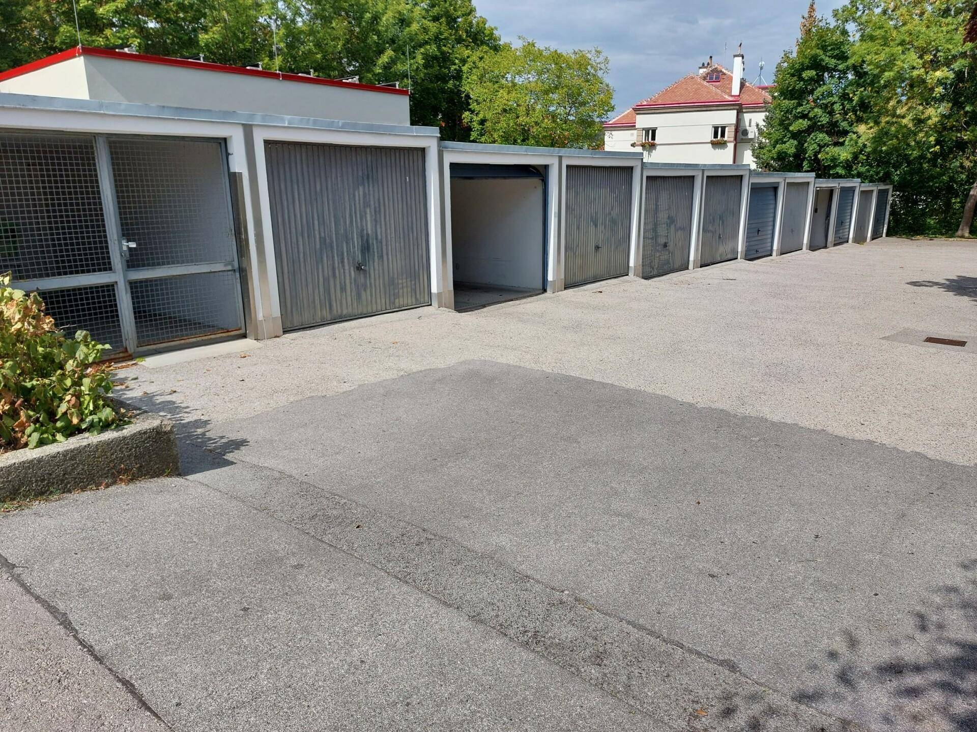 Reihe von Einzelgaragen mit Metalltoren und einem asphaltierten Vorplatz.