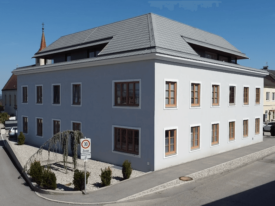 Ansicht eines modernen Gebäudes mit heller Fassade und vielen Fenstern unter blauem Himmel.