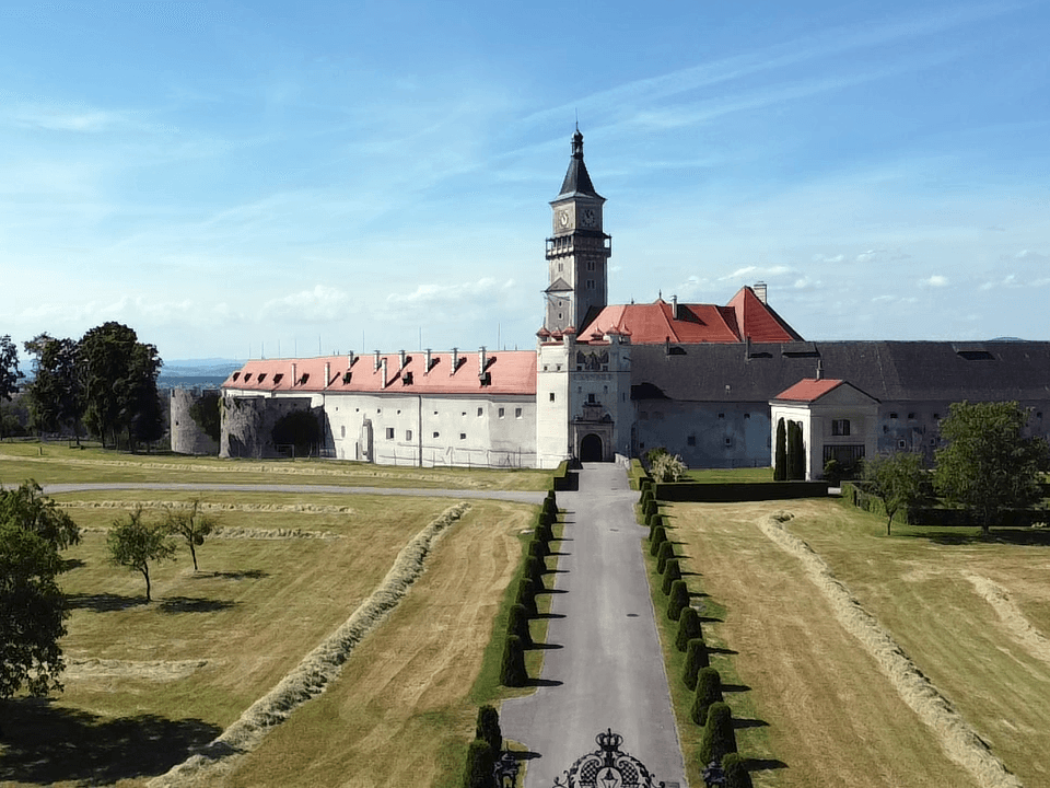 Weitläufige Schlossanlage mit historischer Architektur, großem Vorplatz und gepflegten Grünflächen.
