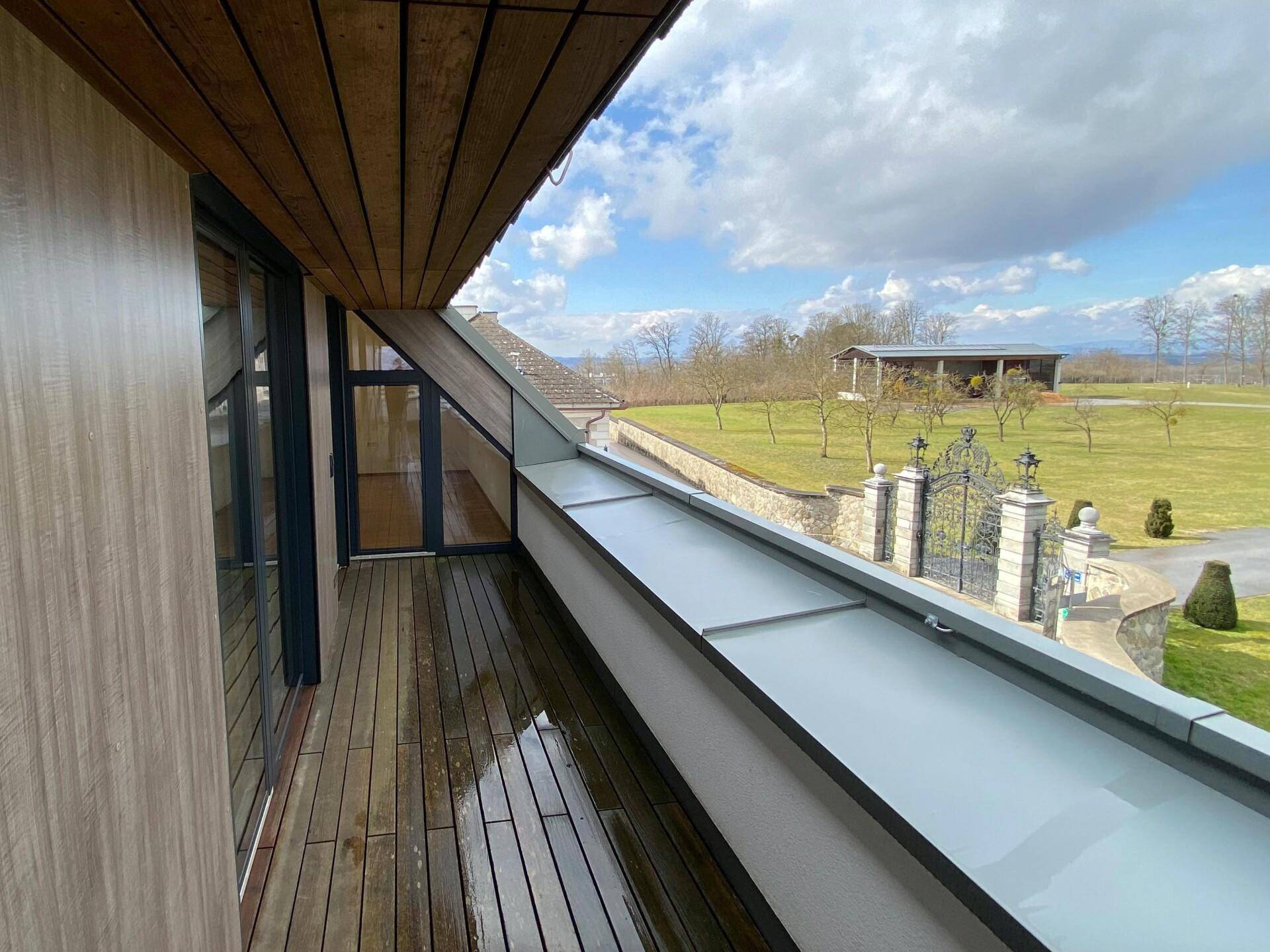 Geräumiger Balkon mit Holzboden und weitem Blick auf die umliegende Landschaft.