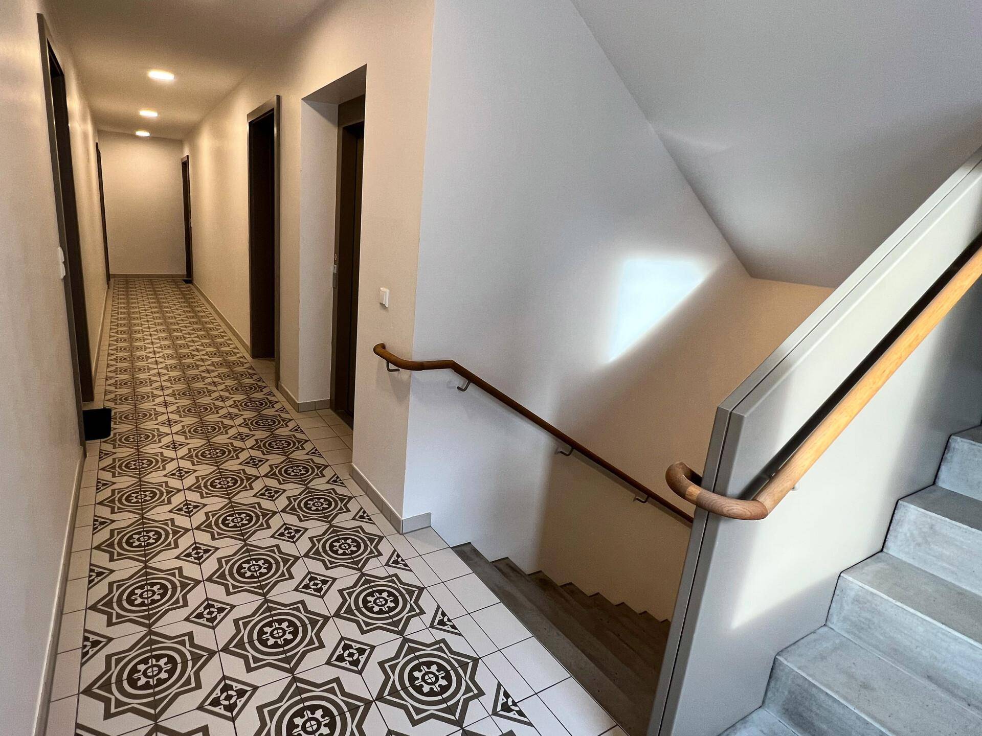 Flur mit dekorativen Fliesen und einer Treppe mit Holzhandlauf, die zu den oberen Etagen führt.