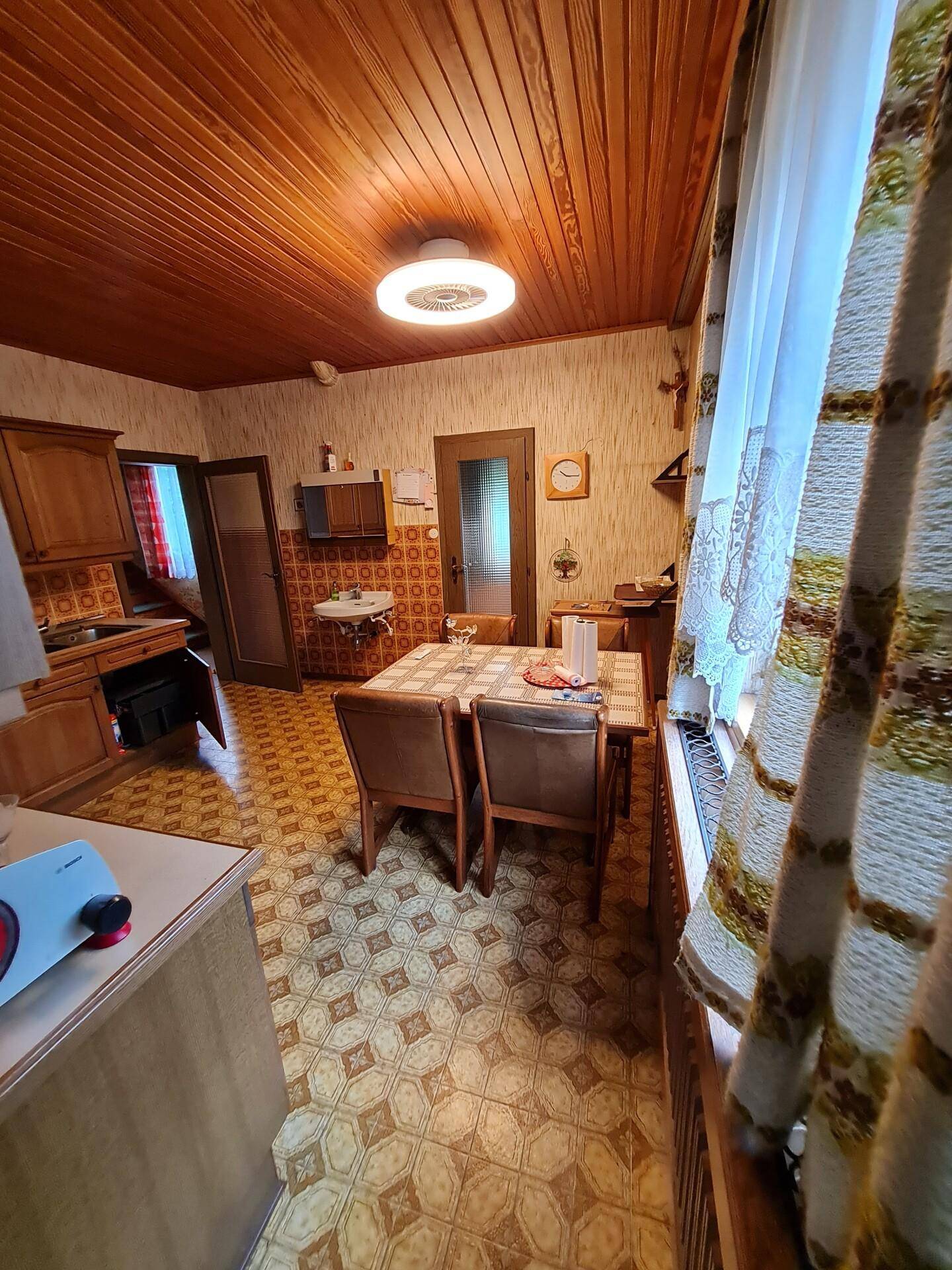 Essbereich in der Küche mit traditionellem Dekor, Holzdecke und Blick nach draußen.