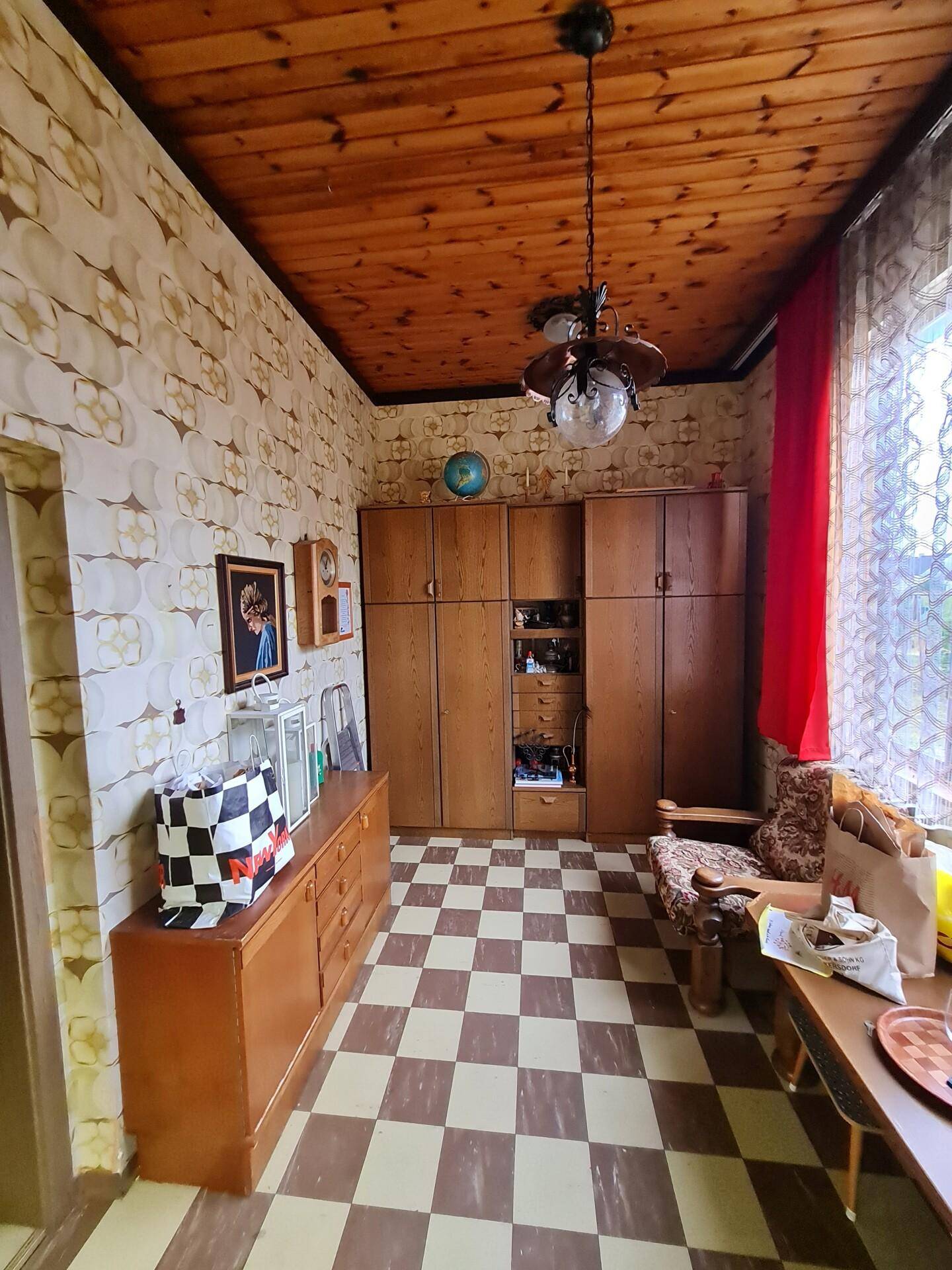 Wohnbereich mit Holzdecke, gemustertem Boden und traditionellen Holzmöbeln.