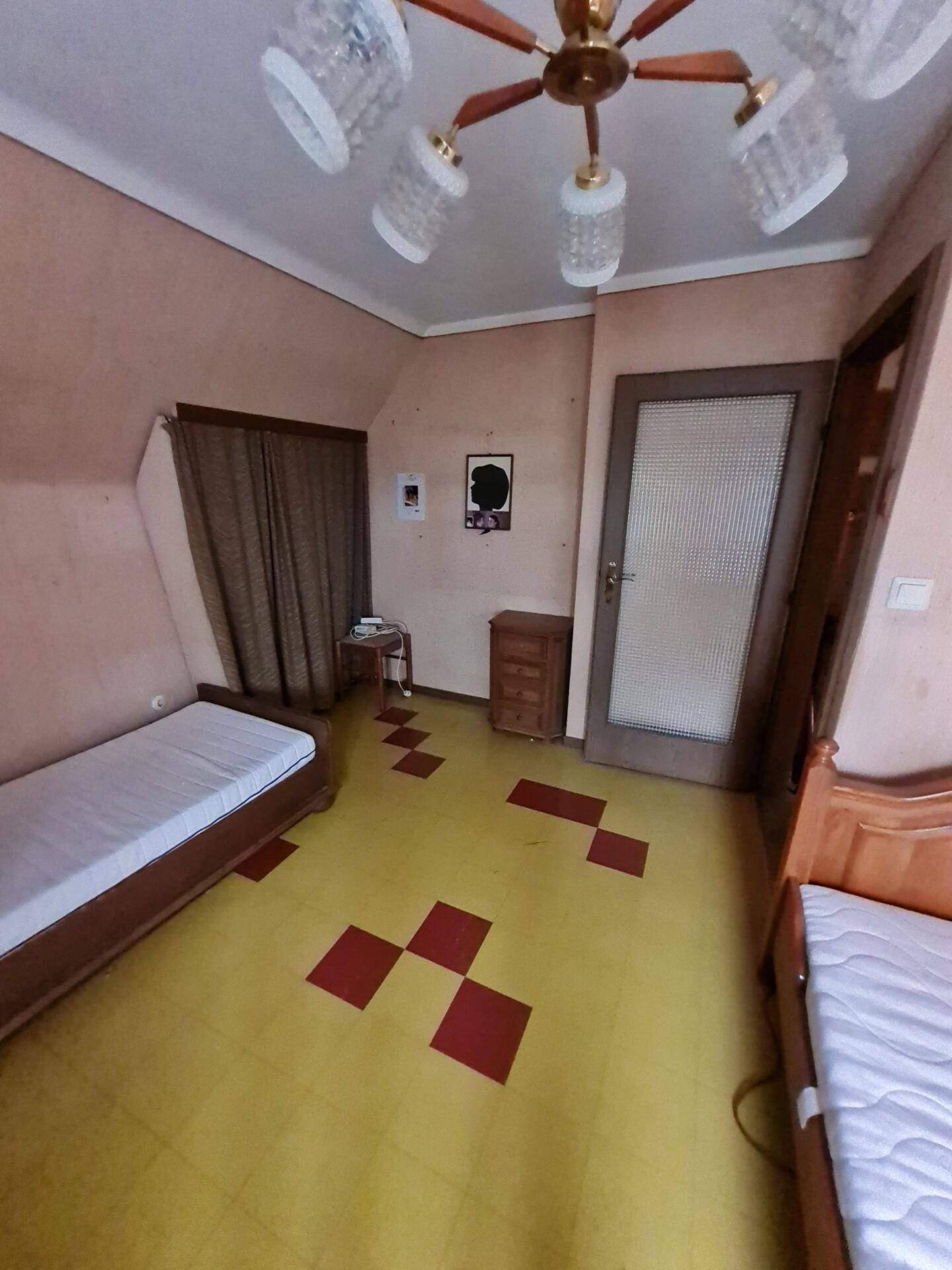 Schlafzimmer mit zwei Einzelbetten, Tür und Fenster, unter einer Dachschräge.