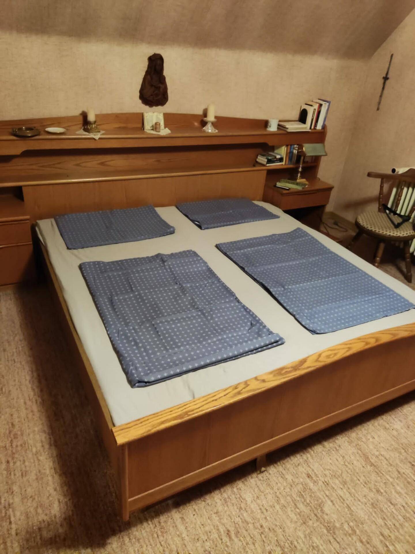 Schlafzimmer mit großem Doppelbett, Holzmöbeln und Teppichboden.