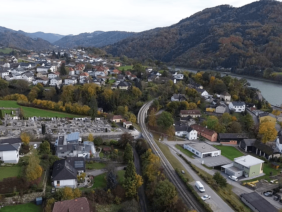 Luftaufnahme einer Stadt am Fluss mit einer Eisenbahnlinie, die sich durch die Landschaft schlängelt.