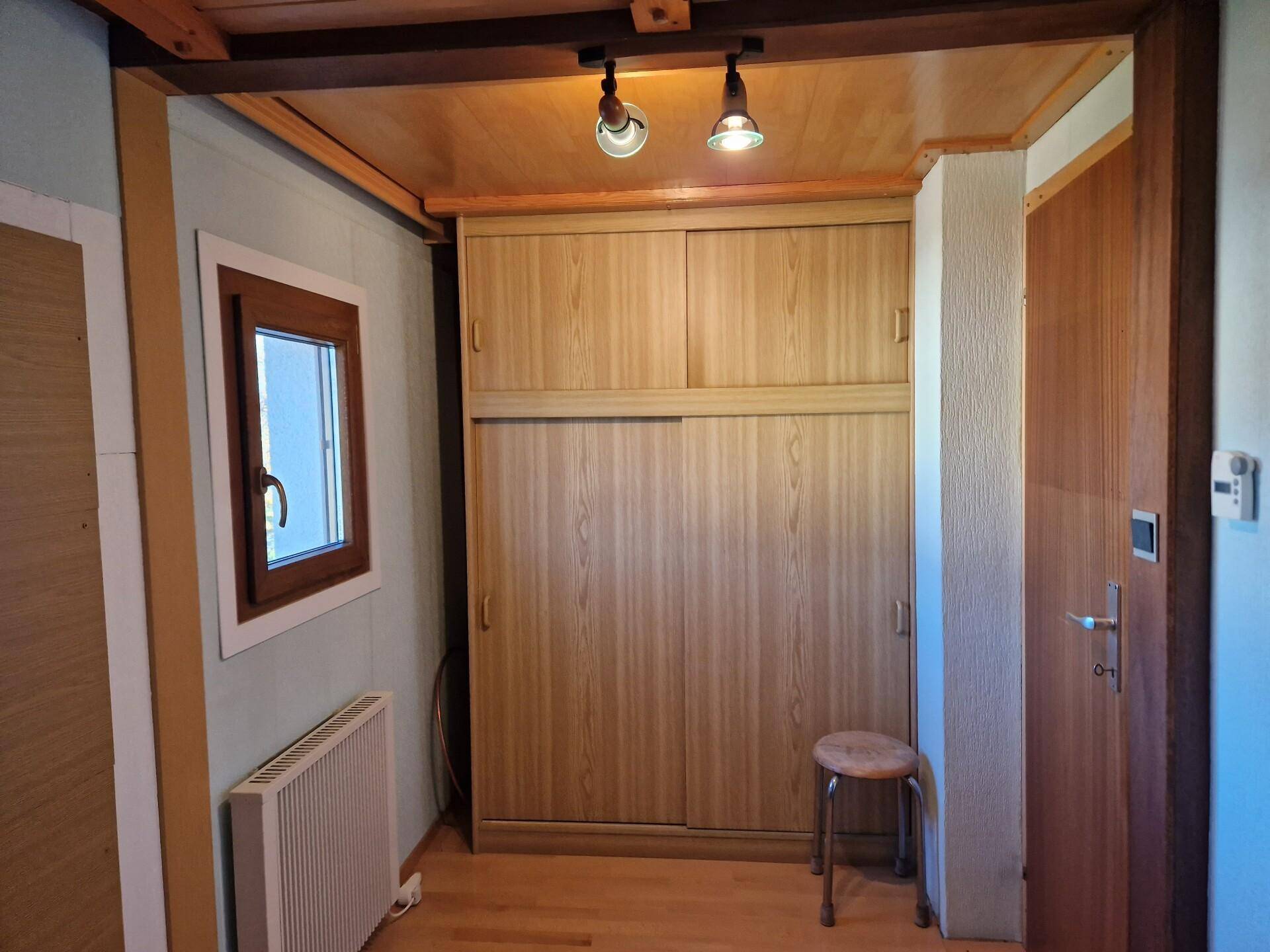 Flur mit Einbauschränken, Holzdecke und Fenster, bietet praktischen Stauraum.