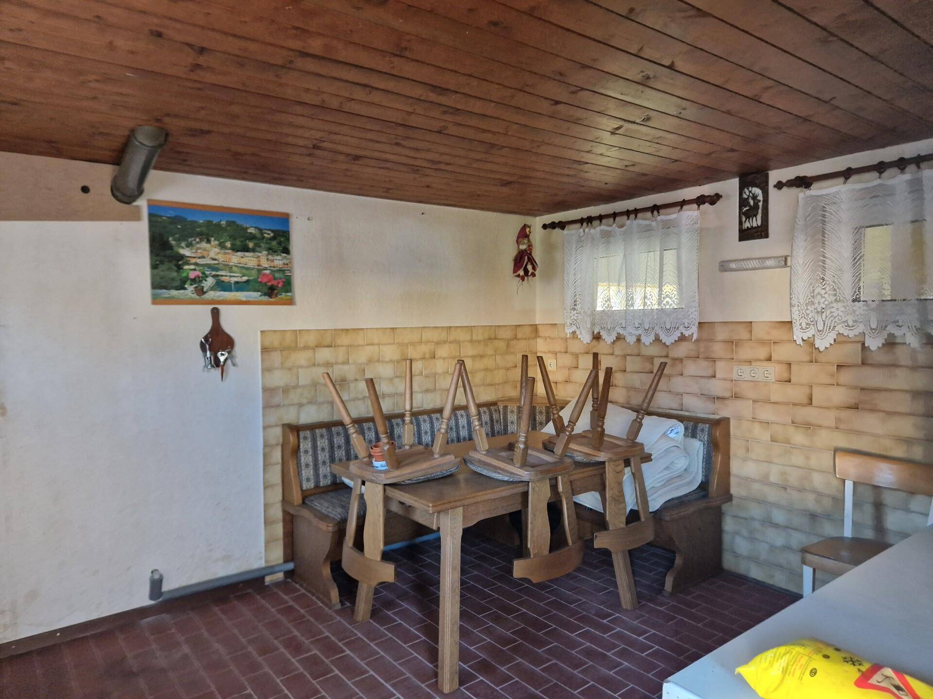Rustikaler Kellerraum mit Holztisch, Bänken und Holzbalkendecke, ideal für gesellige Runden.
