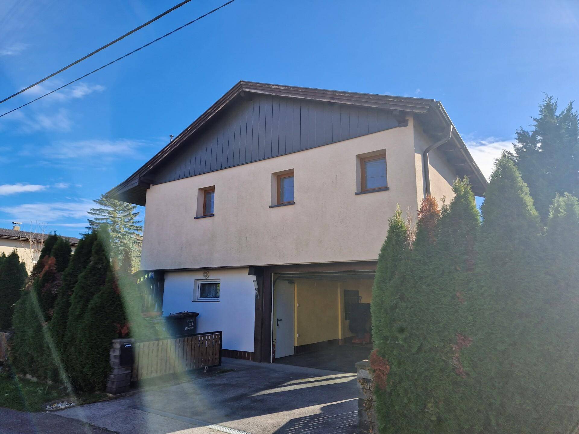 Vorderansicht des Hauses mit Garageneinfahrt und gepflegten Nadelbäumen im Vorgarten.