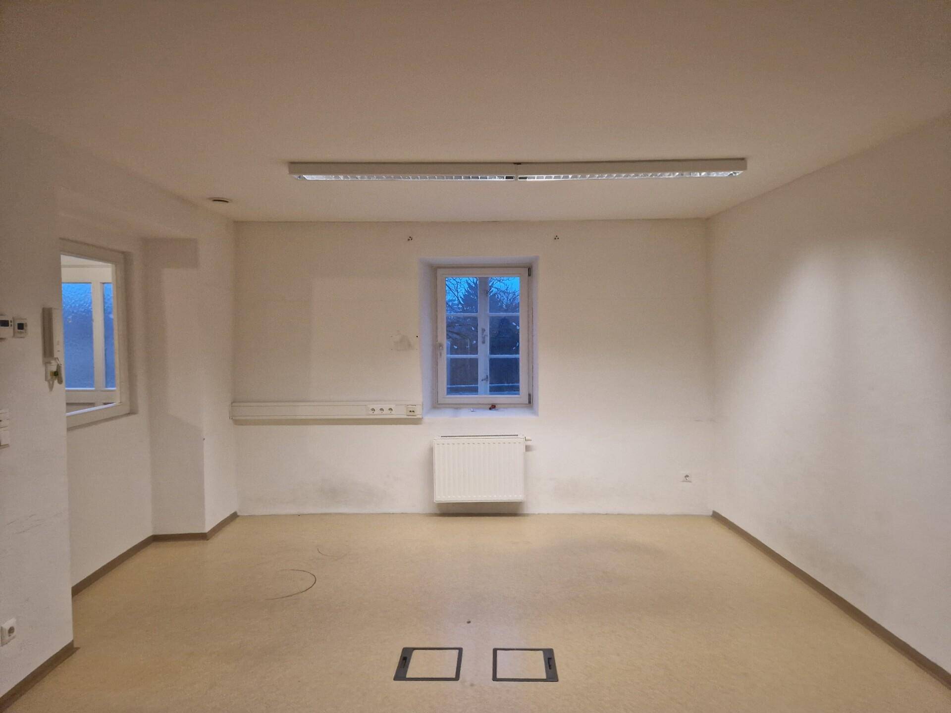 Geräumiger, leerer Raum mit zwei Fenstern, Heizkörper und Linoleumboden, bereit zur Nutzung.