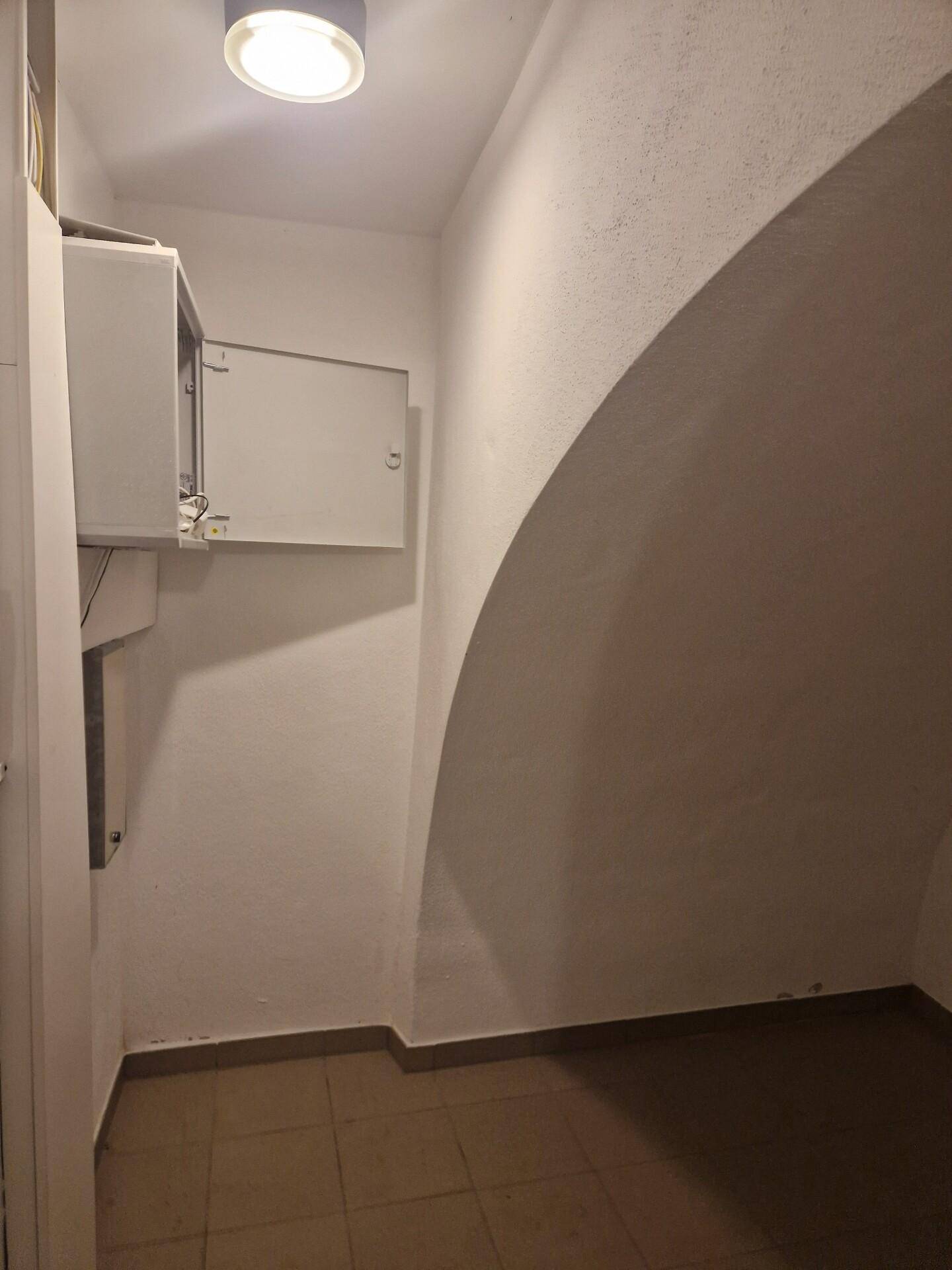 Flur oder Abstellbereich mit gewölbter Decke und einem Sicherungskasten, gefliester Boden.