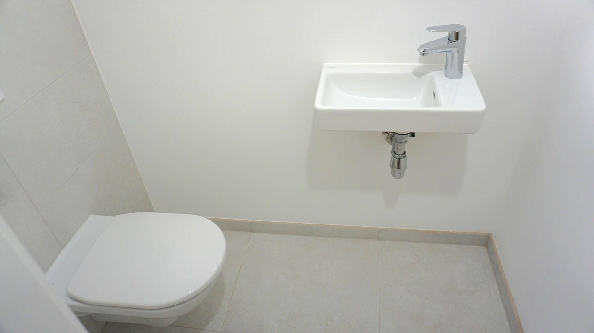 Modernes Gäste-WC mit wandhängender Toilette und kleinem Handwaschbecken.