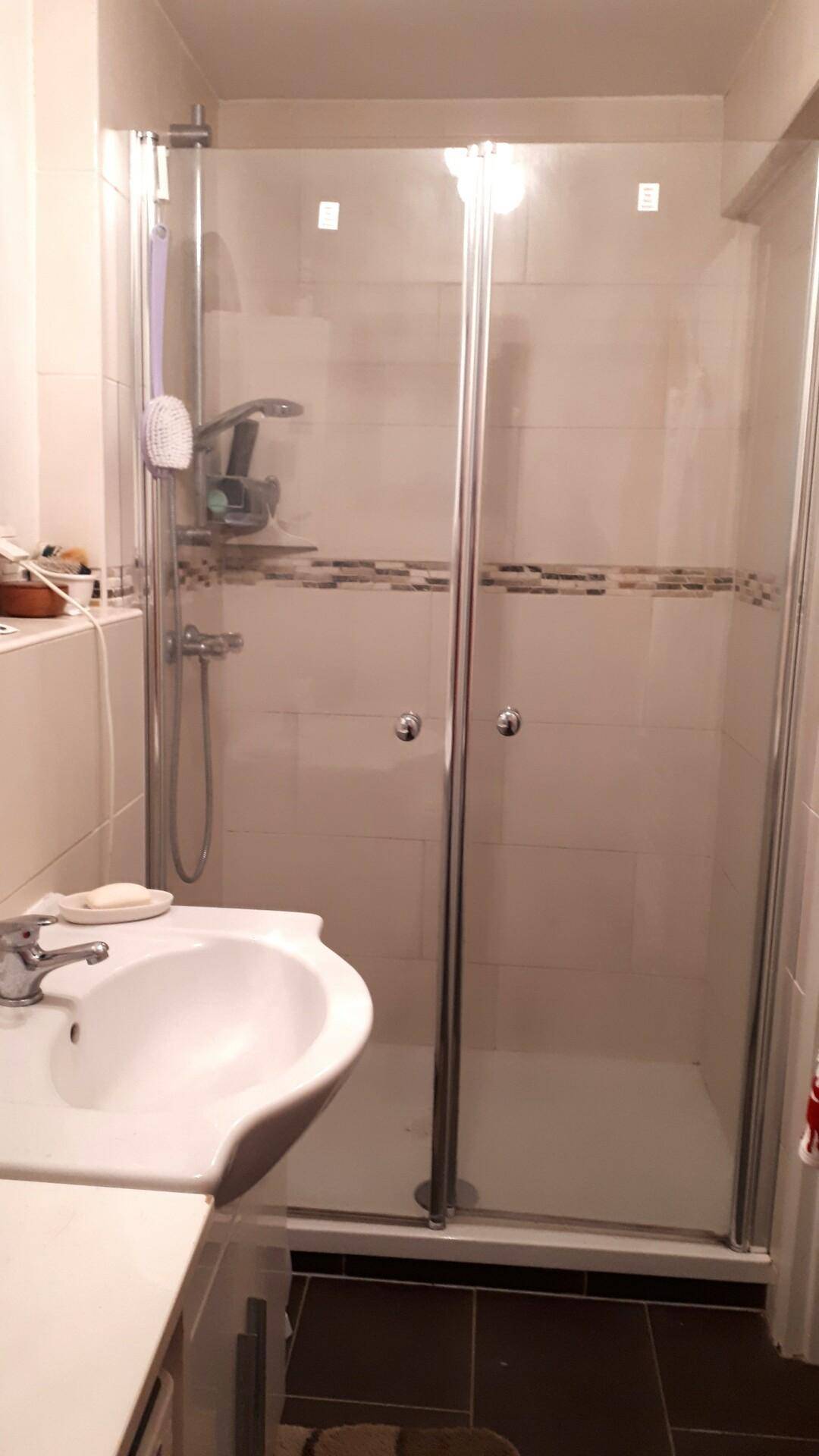 Modernes Badezimmer mit Duschkabine, Waschbecken und hellen Fliesen.